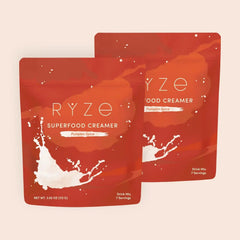 RYZE pumpkin spice superfood creamer packets with milk splash on orange-red background